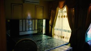 a room with a window with a table and a curtain at The Zabeel Palace Villa in Karachi