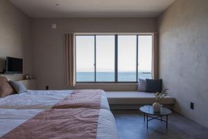um quarto com uma cama e uma grande janela em Nagasaki House Burabura em Nagasaki