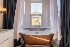 a bath tub in a bathroom with a window at Westfield Lodge: Charming 4 bed, 4 bath house in Broadstairs in Kent