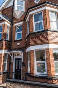 a red brick house with white windows on a street at Westfield Lodge: Charming 4 bed, 4 bath house in Broadstairs in Kent