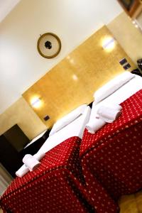 una camera con due letti rossi e un orologio a parete di Hotel Fiorella Milano a Milano