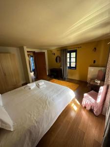 um quarto com uma grande cama branca e pisos em madeira em Arktouros Hotel em Monodendri