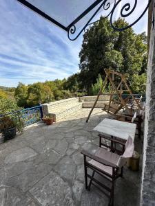 une terrasse avec une table, un banc et une balançoire dans l'établissement Arktouros Hotel, à Monodendri