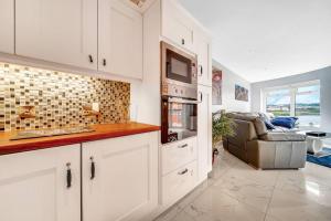 Una cocina con gabinetes blancos y una sala de estar. en The Peace Bridge Apartment, en Derry Londonderry