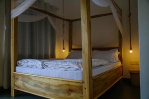 a bedroom with a canopy bed with white sheets at Hakuna Woga Inn in Arusha