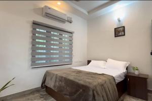 a white bedroom with a bed and a window at Hosted by Resmi Jayalal in Cochin