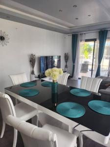 a dining room with a black table and white chairs at appartement pamplemousse in Plaine des Papayes