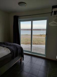 a bedroom with a large window with a view of the ocean at Guesthouse 46 in Hvammstangi
