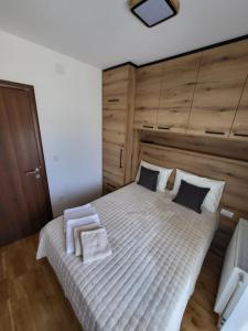 um quarto com uma grande cama branca e uma cabeceira em madeira em Apartman Adam Divčibare em Divčibare