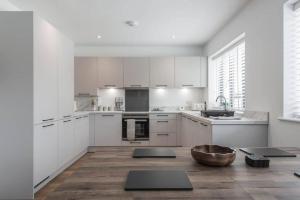 a kitchen with white cabinets and a wooden floor at The Montague: Newly built two bedroom apartment with parking in Kent