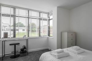 a bedroom with a bed and a desk and windows at The Montague: Newly built two bedroom apartment with parking in Kent