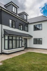 a large black and white house with a yard at The Montague: Newly built two bedroom apartment with parking in Kent