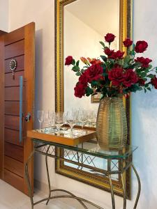 una mesa con copas de vino y un jarrón con rosas rojas en Suites Silva en Capitólio