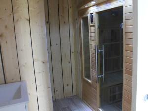 een badkamer met een douche en houten wanden bij Gite les grèves : 15 pers, 300m de la mer + sauna in Saint-Quay-Portrieux