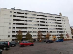 een groot wit gebouw met auto's geparkeerd op een parkeerplaats bij Pet-friendly 4 Bed Apt in Turku with Park views in Turku