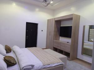 - une chambre avec un lit, une commode et une télévision dans l'établissement HKB APARTMENTS, à Ibadan
