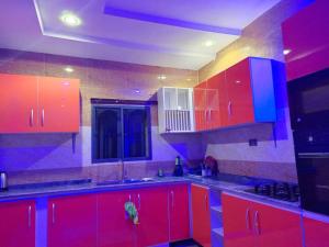 - une cuisine avec des armoires rouges et bleues dans une pièce dans l'établissement HKB APARTMENTS, à Ibadan