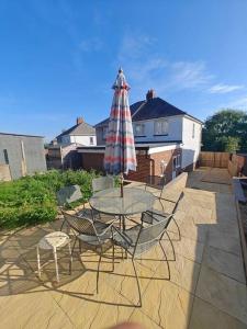 a patio with a table and chairs and an umbrella at Stunning 4 bed House Ideal for Contractors in Southampton
