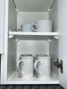 a cupboard with three coffee mugs in it at Tosam Luxury Lodge Two Bedroom Suite in Brampton