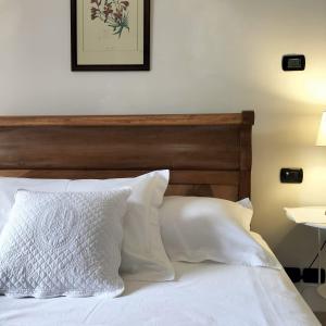 een bed met witte kussens en een houten hoofdeinde bij Stella d'Italia in Sparone