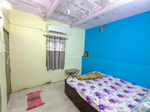 a bedroom with a bed and a blue wall at Rajal Homestay in Dholovira