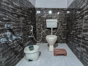 a bathroom with a toilet and a bucket in it at Rajal Homestay in Dholovira