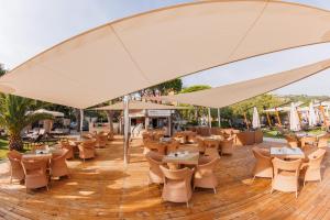 Grand Hotel Portoroz 4* superior – Terme & Wellness LifeClass في بوروتوروج: فناء به طاولات وكراسي تحت مظلة كبيرة
