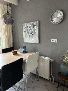 comedor con mesa y reloj en la pared en Vakantiewoning J.W. Schuurmanstraat 14, en Domburg