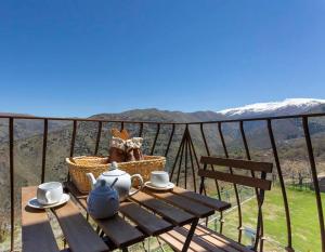 a picnic table on a balcony with a view of the mountains at La Casa del Nogal in Güéjar-Sierra