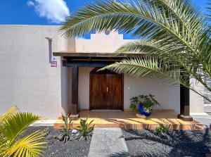 een huis met een houten deur en een palmboom bij Boho Palm in Corralejo