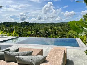 a swimming pool with chairs and a view of a forest at La Résidence - Siargao in General Luna