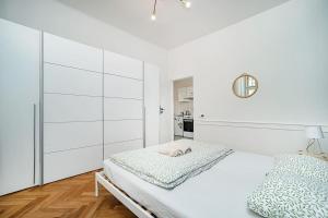 a white bedroom with a bed and a mirror at Cozy apartment in hipster area in Prague