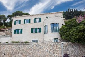 ein Haus an einer Steinmauer mit einem Steinzaun in der Unterkunft Villa Grande Bukovca - Beautiful 5 bedroom villa - Sea views - Glamorous location in Dubrovnik