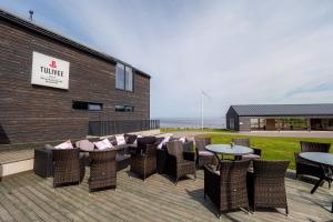 een patio met rieten stoelen en tafels voor een gebouw bij Tulivee Villa in Liimala