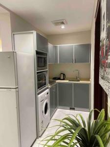 a kitchen with a refrigerator and a washing machine at شقة عصرية واسعة بغرفتي نوم موقع مميز وسط المدينة in Riyadh