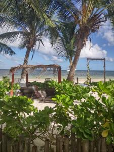 a person sitting on a beach with palm trees at Lunazul Eco-Cabaña Frente al Mar in Mahahual