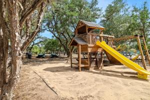 a playground with a yellow slide and a tree at Canyon Lake Cabins in Canyon Lake