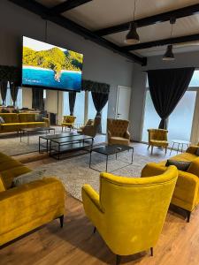 uma sala de estar com cadeiras amarelas e uma televisão de ecrã plano em XXL rooms&spa em Osijek