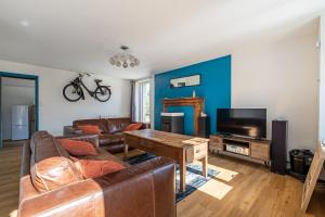 ein Wohnzimmer mit einer Couch, einem Tisch und einem Fernseher in der Unterkunft Le Cottage de Flore - Avec piscine privée chauffée in Saint-Jean-la-Poterie