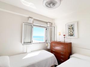 a white bedroom with two beds and a window at Summerlandrota Cordoba8 in Rota