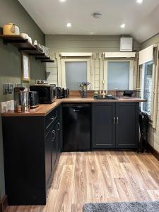 a kitchen with black cabinets and a wooden floor at The Cabin Near Stansted Airport in Little Hallingbury