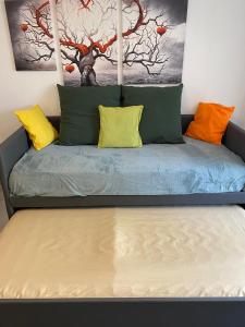 a bed with colorful pillows and a painting on the wall at Ravissant studio au centre ville de Cuges les Pin proche Marseille, Aix, Toulon, plages in Cuges-les-Pins