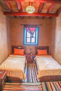 a bedroom with two beds and a window at MAISON D'HOTE DAR IMRANE in Tatta