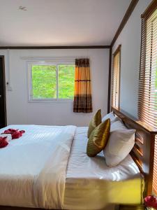 a bedroom with a bed with pillows and a window at Khaosok River Camp in Khao Sok