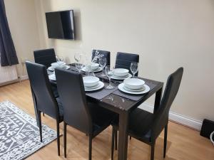 uma mesa de jantar preta com cadeiras e copos de vinho em Tooting Bec Central Apartment by London Tube em Londres