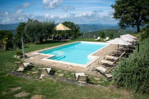 una piscina con sedie e ombrelloni in un cortile di Villa Val di Luce - Homelike Villas a Umbertide