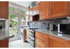 uma cozinha com armários de madeira e um forno com placa de fogão em Chic 4BR Home in Mitcham Ideal for Families em Mitcham