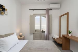 a white bedroom with a bed and a mirror at New Sea Serenity Villas Next to the Sea With Private Jacuzzi in Vlychada