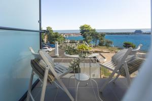 2 Stühle und ein Tisch auf dem Balkon mit Blick auf das Wasser in der Unterkunft Villa Arausa in Vodice