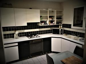 una cucina con mobili bianchi e un lavandino di Chambre Calme meublé proche aéroport rocade a Pessac